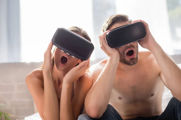 Shocked couple touching vr headsets in bedroom — Stock Photo