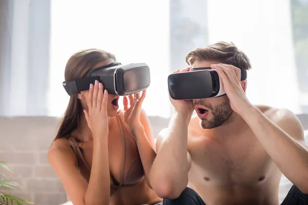 Shocking couple using and touching vr headsets in bedroom — Stock Photo