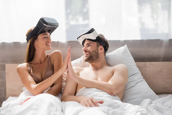 Young lovers with vr headsets looking at each other and giving high five — Stock Photo