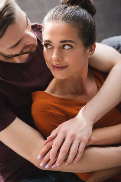 Jovem mulher olhando para o namorado concurso abraçando-a de volta — Fotografia de Stock