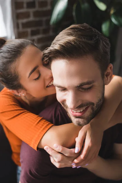 Happy woman hugging neck of smiling boyfriend and whispering in his ear — Stock Photo