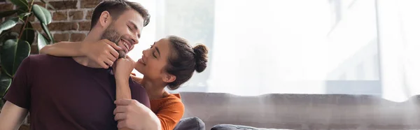 Mujer feliz tocando la cara del hombre sonriente en casa, bandera - foto de stock