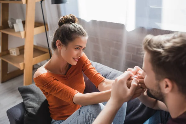 Glückliche Frau sieht zarten Freund an, der ihre Hände auf verschwommenem Vordergrund küsst — Stockfoto