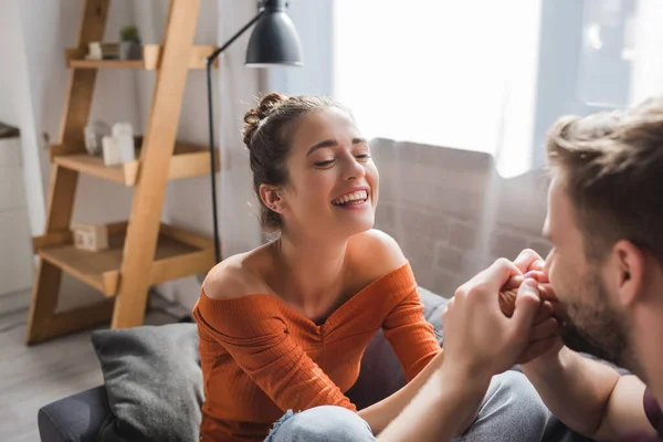 Cheerful woman looking at beloved man kissing her hands on blurred foreground — Stock Photo