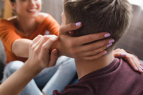 Mujer joven tocando la cabeza del hombre amado sobre fondo borroso - foto de stock