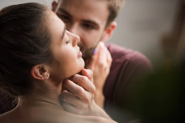 Tender man touching face ow beloved girlfriend with closed eyes on blurred background — Stock Photo