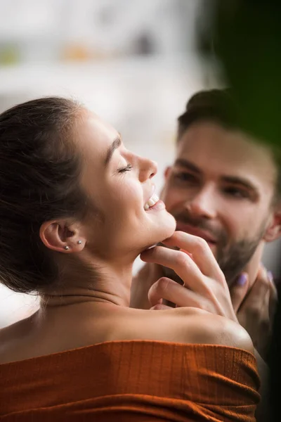 Young man touching face of happy girlfriend on blurred background — Stock Photo