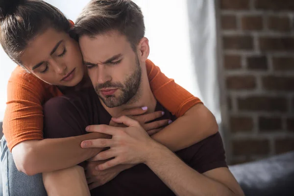 Responsive woman embracing frustrated man sitting with closed eyes — Stock Photo