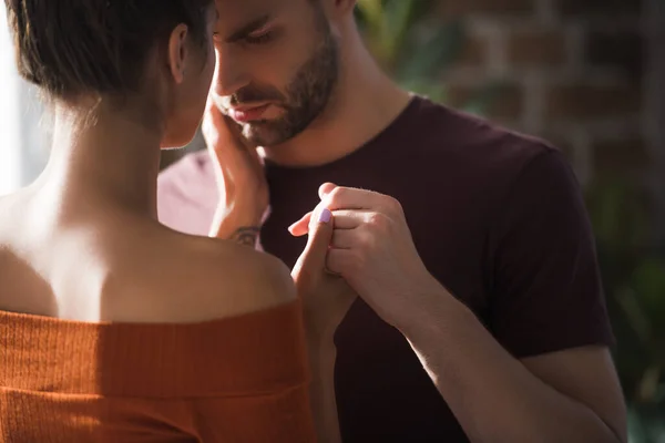 Back view of young woman touching hand and face of depressed man standing with closed eyes — Stock Photo