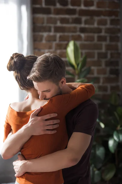 Rückseite der liebevollen Frau, die besorgten Mann zu Hause umarmt — Stockfoto