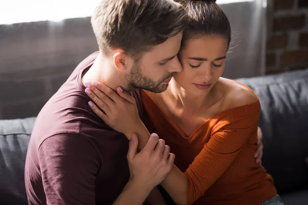 Worried woman and young man hugging while sitting on sofa — Stock Photo