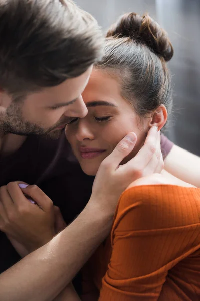 Tender man hugging and touching face of depressed girlfriend at home — Stock Photo