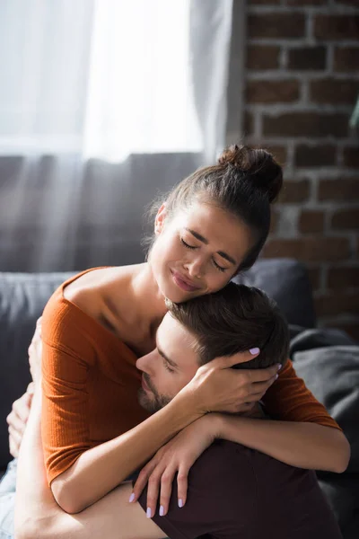 Crying woman embracing beloved man while sitting on sofa — Stock Photo