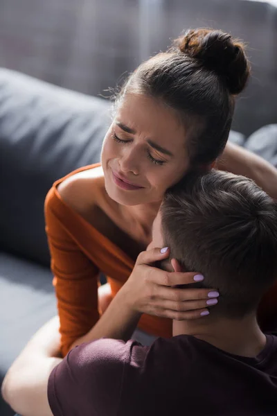 Crying woman touching head of beloved boyfriend while sitting on sofa — Stock Photo