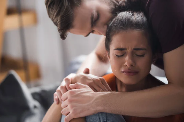 Tender man hugging and kissing head of upset girlfriend crying with closed eyes — Stock Photo