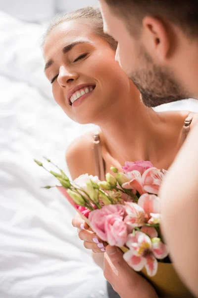Homme embrassant petite amie heureuse tenant des fleurs avec les yeux fermés — Photo de stock
