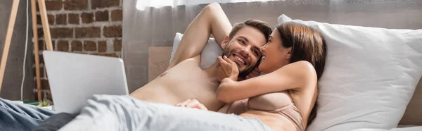 Sensual mulher tocando rosto de sexy namorado enquanto deitado na cama juntos, banner — Fotografia de Stock