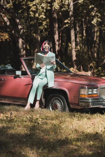 Femme élégante regardant la carte près de la voiture pendant le voyage — Photo de stock