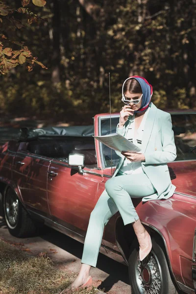 Pensive woman in sunglasses looking at map near car on road — Stock Photo