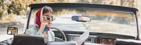 Pensive woman looking at map in retro car on road, banner — Stock Photo