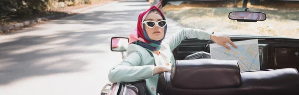 Елегантна жінка тримає карту на водійському сидінні старовинного автомобіля, банер — стокове фото