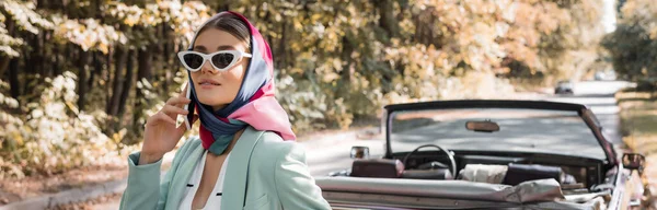 Femme à la mode parlant sur smartphone pendant le voyage en voiture sur la route, bannière — Photo de stock