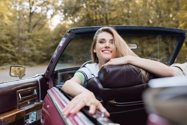 Cheerful woman looking away while sitting in vintage cabriolet, banner — Stock Photo