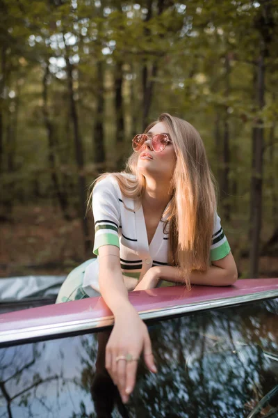 Mulher elegante olhando para longe, enquanto em pé em cabriolet em primeiro plano borrado — Fotografia de Stock