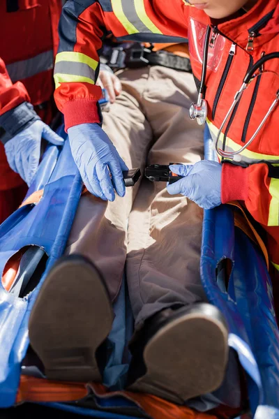 Concentration sélective des ceintures de verrouillage paramédicale de la civière près du patient et du collègue dans des gants en latex — Photo de stock