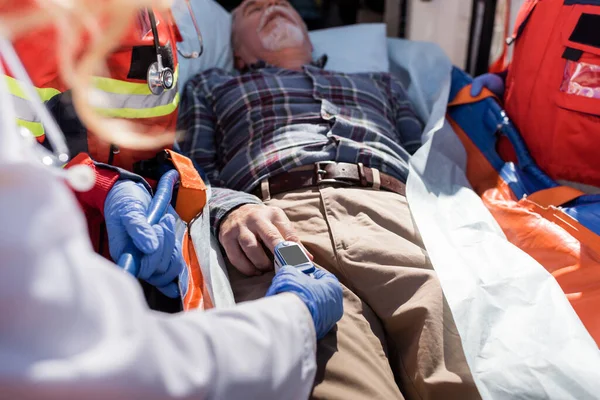 Focus selettivo del cardiofrequenzimetro a digiuno medico sul paziente vicino ai paramedici e all'ambulanza — Foto stock