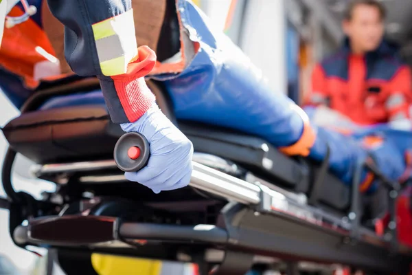 Selective focus of paramedic in latex glove holding stretcher with patient outdoors — Stock Photo