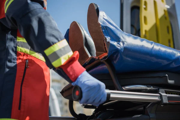 Cropped view of paramedic holding stretcher with patient outdoors — Stock Photo