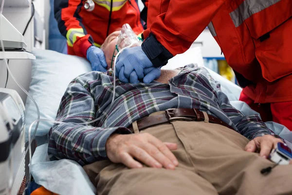 Focus selettivo del paramedico che fa rianimazione cardiopolmonare al paziente in maschera di ossigeno in ambulanza — Foto stock