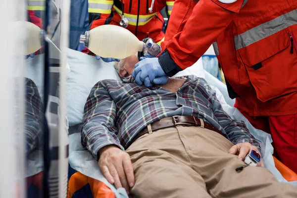 Selective focus of paramedics doing cardiopulmonary resuscitation with bag valve mask to sick patient during first aid — Stock Photo