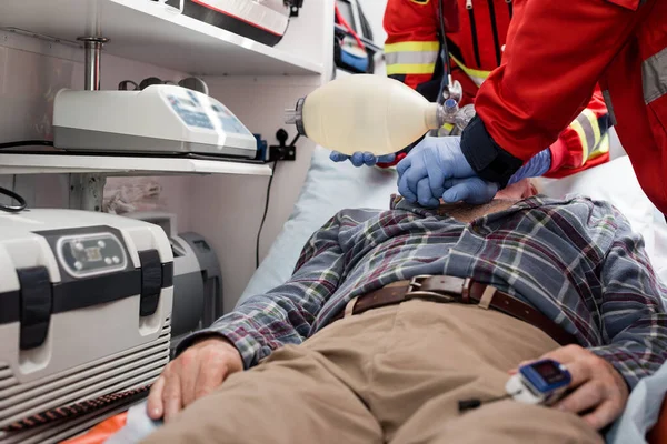 Focus selettivo dei paramedici che effettuano la rianimazione cardiopolmonare al paziente con cardiofrequenzimetro in ambulanza — Foto stock