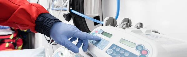 Panoramic shot of paramedic in latex glove using equipment in ambulance car — Stock Photo