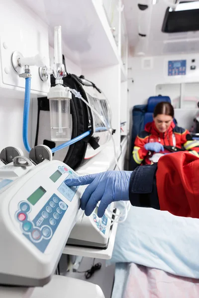 Selective focus of paramedic using equipment near colleague in ambulance car — Stock Photo