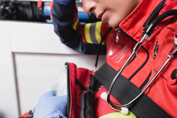 Vista recortada de paramédico con estetoscopio en coche ambulancia - foto de stock