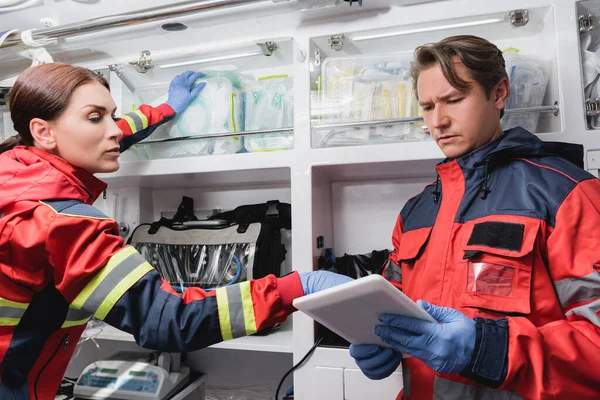 Paramédicos utilizando tableta digital durante el inventario en coche ambulancia - foto de stock