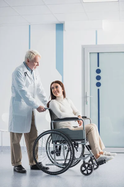 Behinderter Patient sitzt im Rollstuhl neben Oberarzt in Klinik — Stockfoto