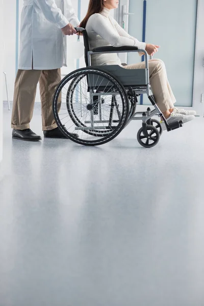 Vue recadrée du médecin debout près du patient en fauteuil roulant à la clinique — Photo de stock