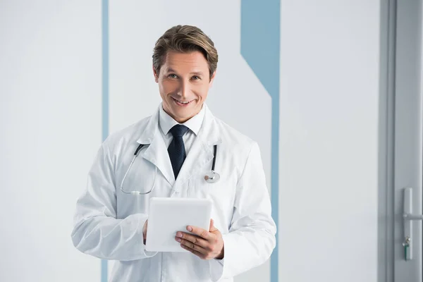 Doctor looking at camera while using digital tablet in hospital — Stock Photo