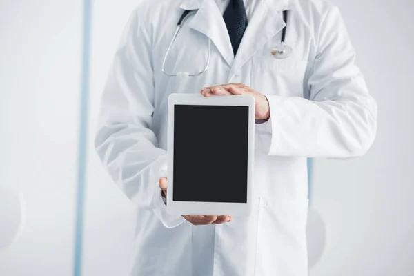 Vista recortada do médico mostrando tablet digital com tela em branco no hospital — Fotografia de Stock