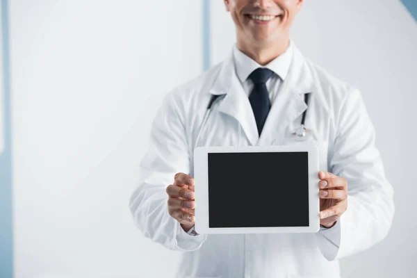 Vista recortada del médico sosteniendo tableta digital con pantalla en blanco en el hospital - foto de stock