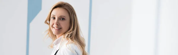 Panoramic shot of blonde doctor looking at camera in clinic — Stock Photo