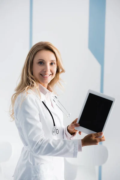 Blonde doctor showing digital tablet with blank screen in clinic — Stock Photo