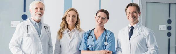 Website header of nurse and doctors with stethoscopes looking at camera in clinic — Stock Photo