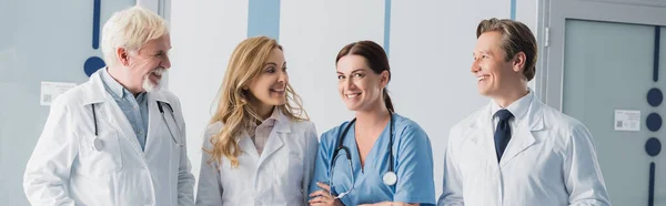 Panoramic shot of doctors looking at nurse in clinic — Stock Photo