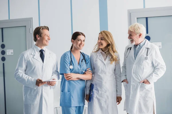 Лікарі з буфером і цифровим планшетом дивляться на медсестру в клініці — стокове фото