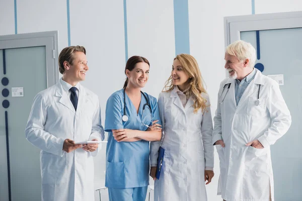 Doctors with clipboard and digital tablet looking at nurse in clinic — Stock Photo